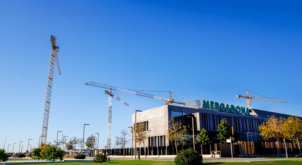 Exterior of a Mercadona supermarket under construction with cranes in the background