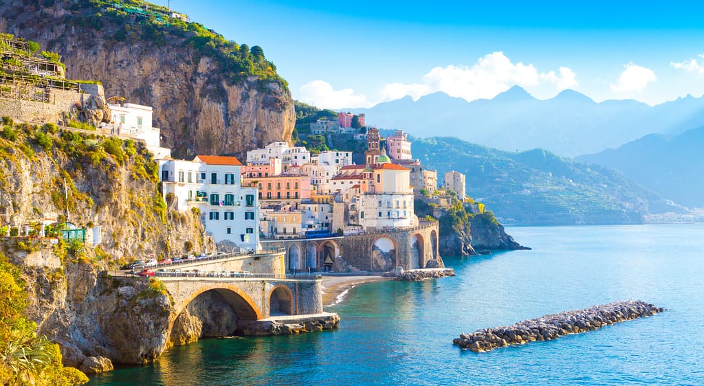 Picturesque view of a coastal village on the Amalfi Coast, with colorful buildings perched on cliffs above the sea.